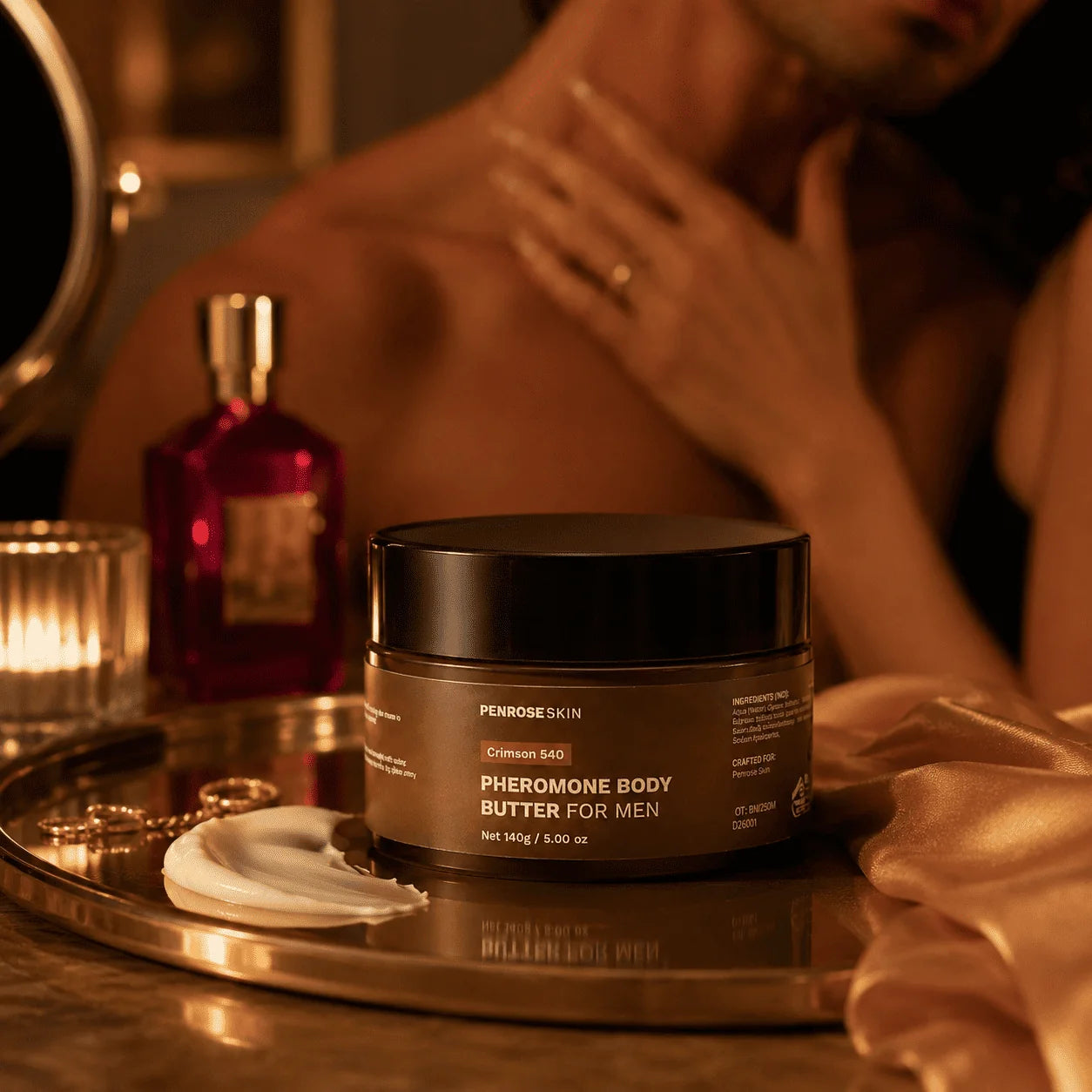 Penrose Skin body butter on a gold tray beside a fragrance bottle in candlelight